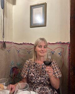 Chef Deb in restaurant in Spain, drinking a glass of wine