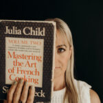 Chef Deb holding a copy of Julia Child's Mastering the Art of French Cooking.