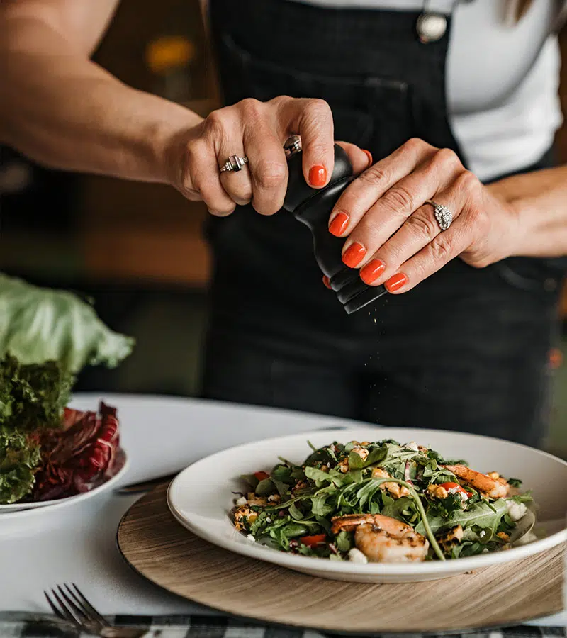 Chef Deb Silver adds pepper to a shrimp BLT summer salad at side dish carryout resturant in rochester michigan